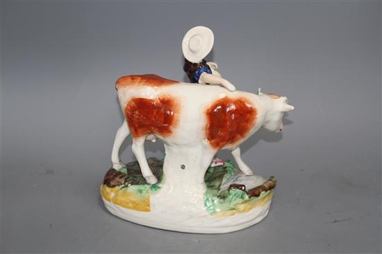 A Staffordshire pottery group of a milkmaid and cow, L. 21cm